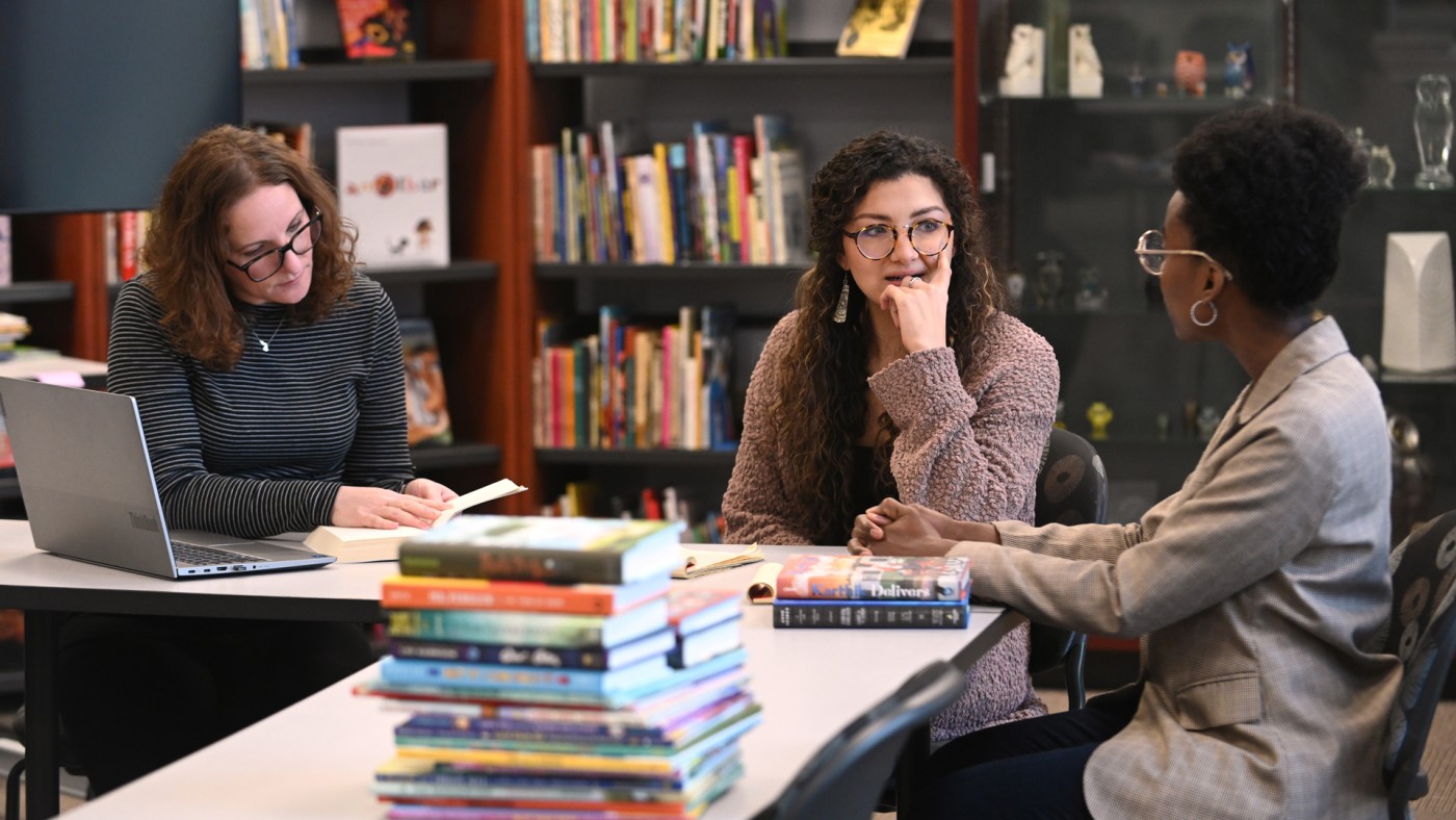 Three inddividuals at a table with books