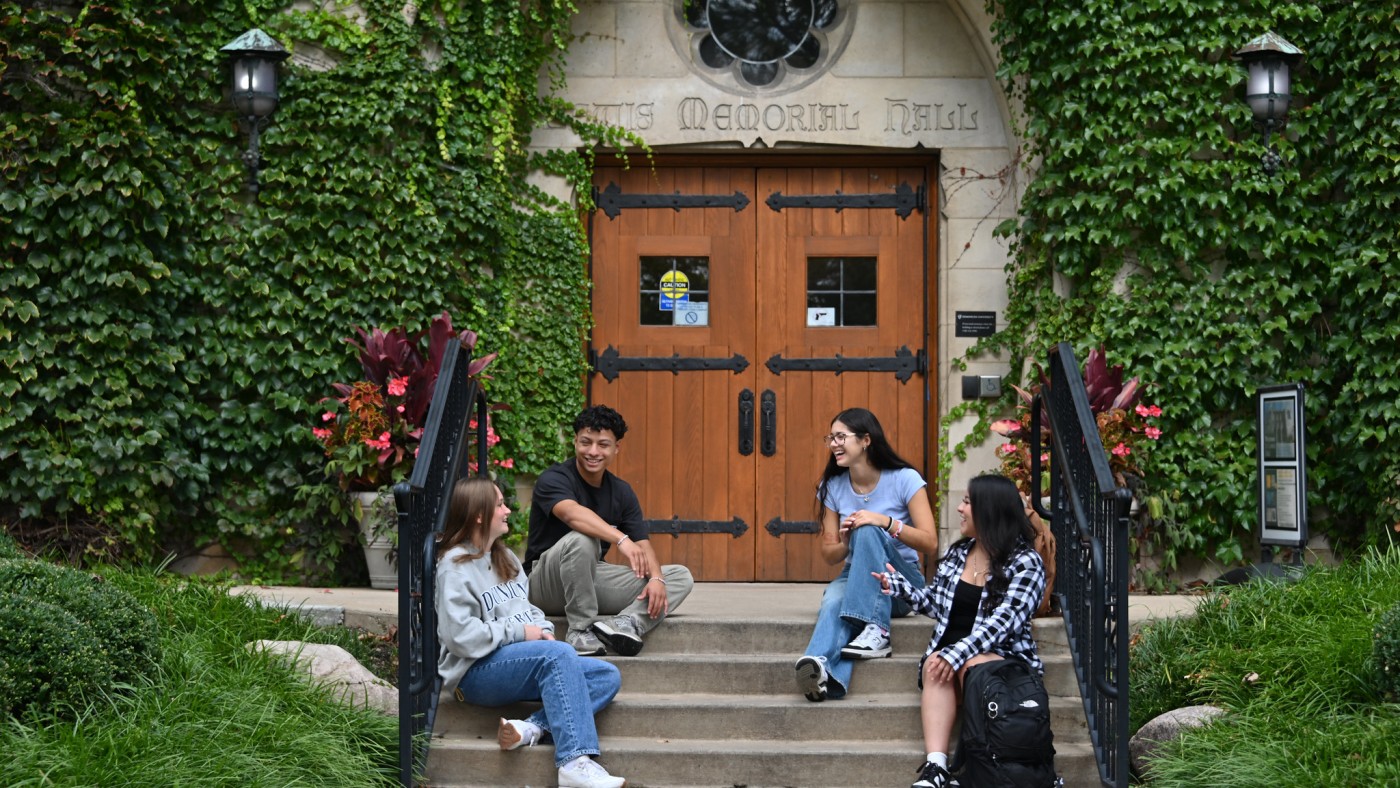 Four students seated on steps of campus building