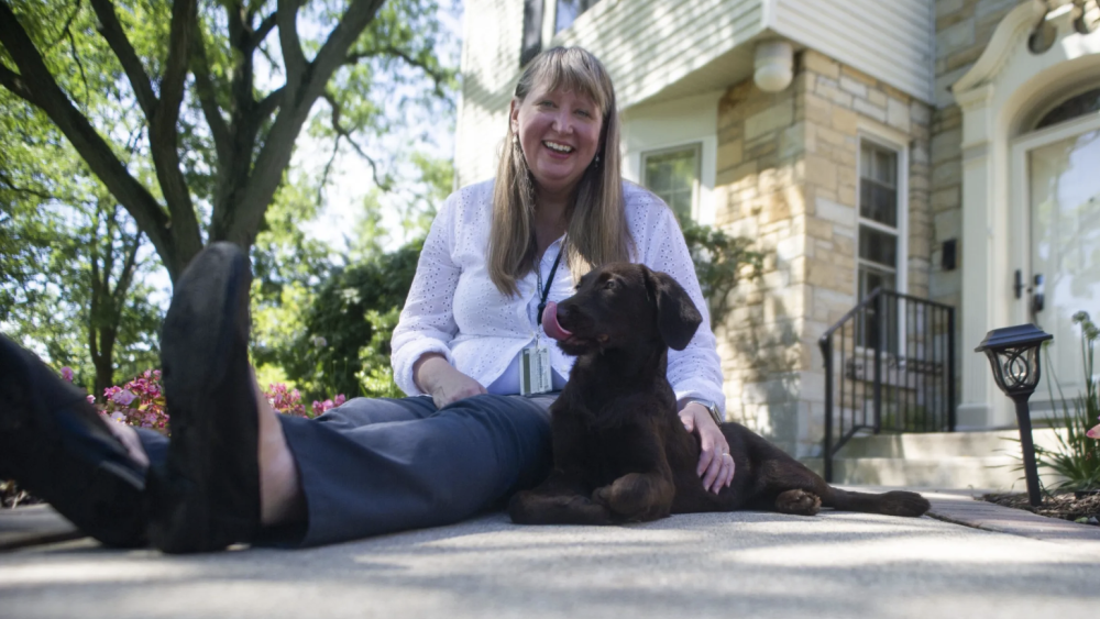 Dominican University President Glena G. Temple sits in front of the president's house with dog, Rosie Bea.