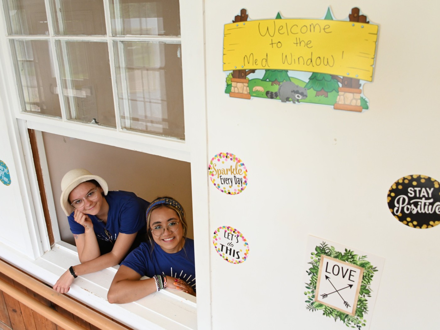 Two students looking out window, building signage