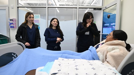 Three students observing patient in hospital bed