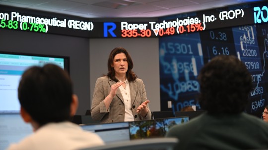 Female speaker with tickertape in background